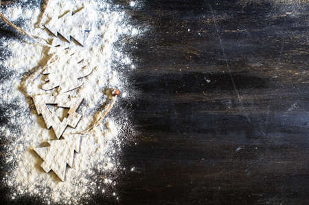 Christmas time cooking concept with flour and cookies forms on dark wooden tableの写真素材