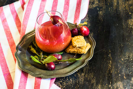 Plum cake and fresh plums with glass of juice on rustic tableの写真素材