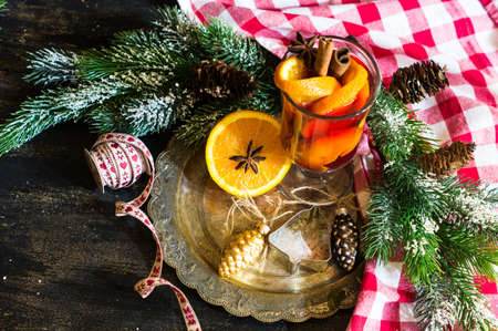 Mulled wine in a glass and christmas time decorations on rustic wooden tableの写真素材