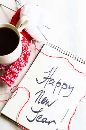 Cup of coffee with bright red scarf and christmas time decorations on wooden table with copyspaceの写真素材