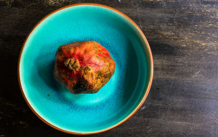 Ripe pomegranate on the vintage plate on dark rustic wooden table with copyspaceの写真素材