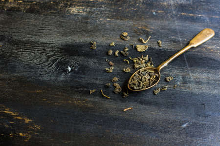 Vintage tea spoon with green tra leaves on dark wooden table with copy spaceの写真素材