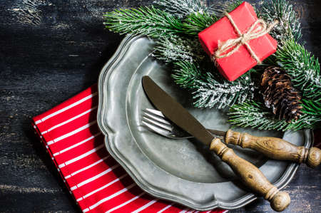 Christmas time table setting with bright red napkin, vintage plate and silverware and Christmas...