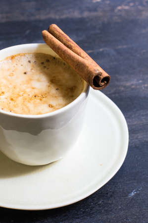 Cup of cappuccino with cinnamon spice and Christmas decoration on dark rustic backgroundの写真素材