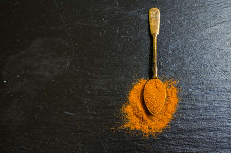 Different types of pepper spice in vintage spoons on black stone backgroundの写真素材