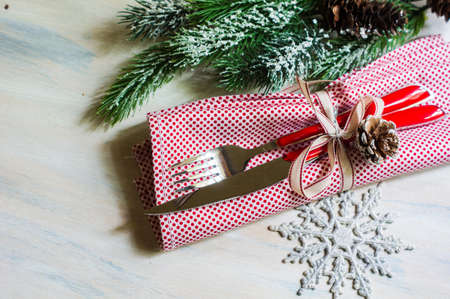 Christmas table setting with bright napkin, spices, decorations and vintage silverware on rustic wooden tableの写真素材