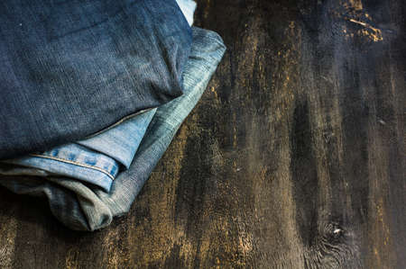 Different color jeans stacked on a wooden backgroundの写真素材