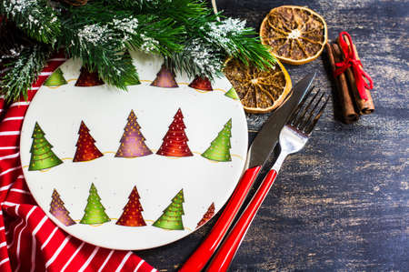 Christmas table setting with bright napkin, spices, decorations and vintage silverware on rustic wooden tableの写真素材