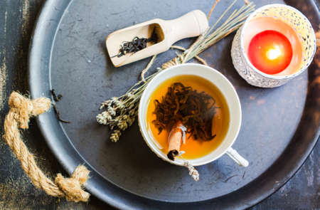 Cup of black tea with cinnamon and lavender, wooden spoon with tea leaves on rustic wooden table with copyspaceの写真素材