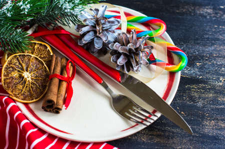 Christmas table setting with bright napkin, spices, decorations and vintage silverware on rustic wooden tableの写真素材