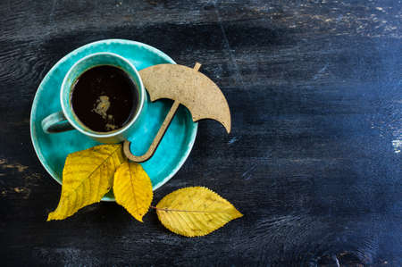 Cup of coffee with bright yellow leaves on rustic wooden table with copyspaceの写真素材