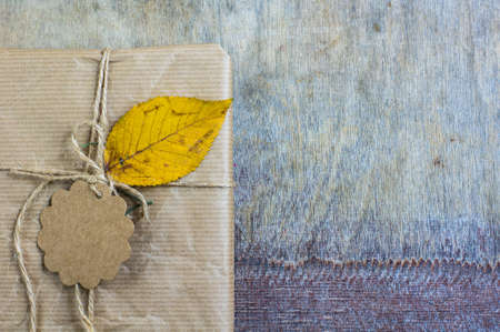 Present box decorated with autumnal yellow leaveas and berries on rustic backgroundの写真素材