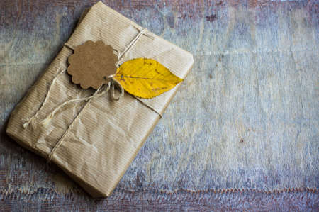 Present box decorated with autumnal yellow leaveas and berries on rustic backgroundの写真素材