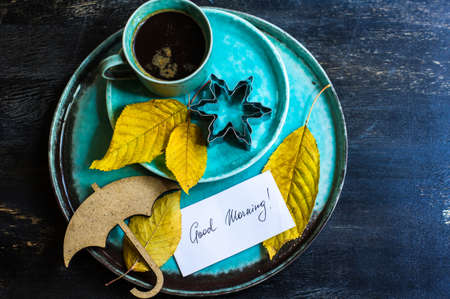 Cup of coffee with bright yellow leaves on rustic wooden table with copyspaceの写真素材