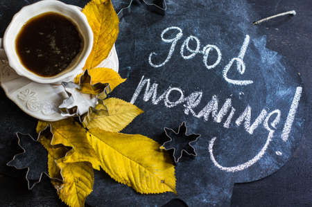 Cup of coffee with bright yellow leaves on rustic wooden table with copyspaceの写真素材