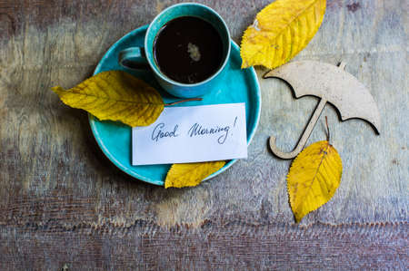 Cup of coffee with bright yellow leaves on rustic wooden table with copyspaceの写真素材