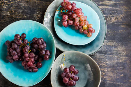 Fresh organic grape fruits and rustic plates on dark old wooden tableの写真素材