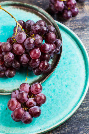 Fresh organic grape fruits and rustic plates on dark old wooden tableの写真素材