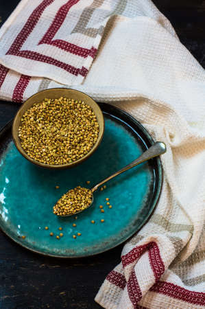 Organic buckwheat in a vintage bowl with spoon on dark rustic table