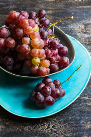 Fresh organic grape fruits and rustic plates on dark old wooden tableの写真素材