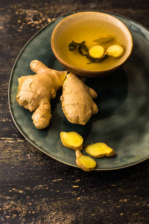 Cup of tea with ginger on dark wooden table