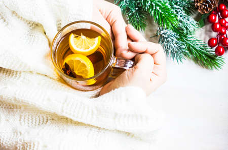 Cup of Tea with a Lemon and Cinnamon in the hands in knitted sweeter on Christmas background in rustic style with copyspaceの写真素材