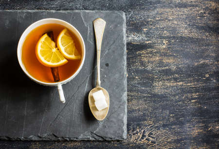 Cup of tea with lemon and spoon with sugar on dark wooden tableの写真素材
