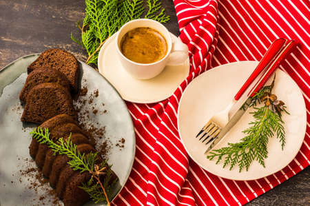 Tasty Christmas chocolate cake on rustic plate and cup of coffee on dark wooden table