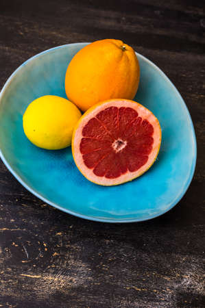 Bright organic grapefruit slice on rustic plates on dark wooden table with copyspaceの写真素材