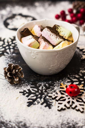 Christmas or New Year composition with hot chocolate and marshmallows, decorated with fir cones and holiday balls and jingle bells on  dark vintage wooden background,の写真素材