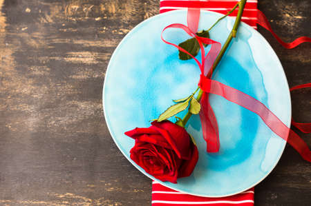 Festive table seting with red rose and heart on dark rustic table with copyspaceの写真素材