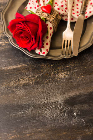 Festive table seting with red rose and heart on dark rustic table with copyspaceの写真素材
