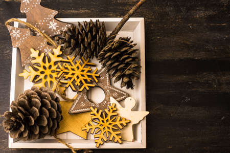 Christmas concept with rustic wooden festive christmas decorations and pine cones on dark wooden backgroundの写真素材