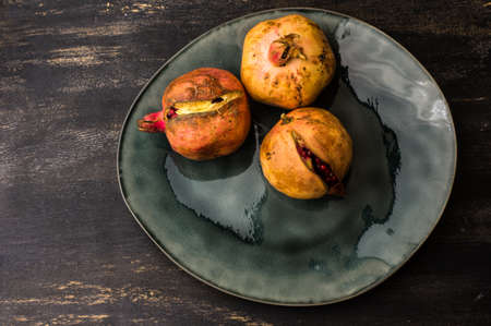 Ripe organic pomegranate fruits on bright plates on dark rustic wooden table