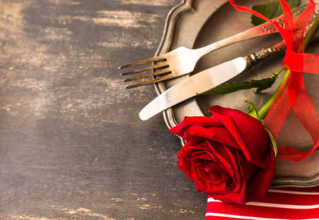 Festive table seting with red rose and heart on dark rustic table with copyspaceの写真素材