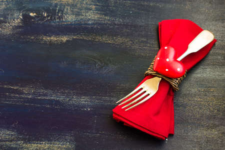 Festive table setting with red rose and heart on rustic wooden table with copyspaceの写真素材