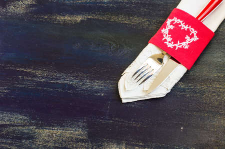 Festive table setting with red rose and heart on rustic wooden table with copyspace
