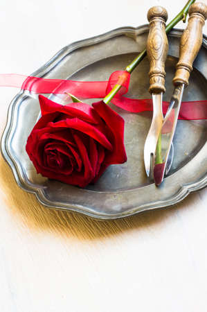 Festive table setting with red rose and heart on rustic wooden table with copyspaceの写真素材