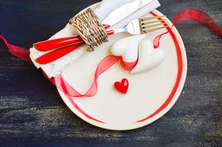 Festive table setting with red rose and heart on rustic wooden table with copyspaceの写真素材