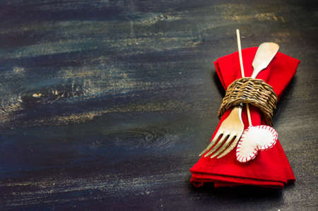 Festive table setting with red rose and heart on rustic wooden table with copyspace