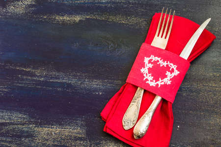 Festive table setting with red rose and heart on rustic wooden table with copyspaceの写真素材