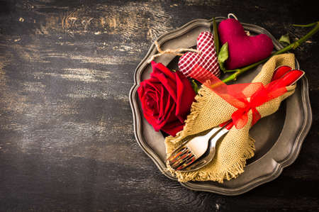 Festive table setting with red rose and heart on dark rustic table with copyspaceの写真素材