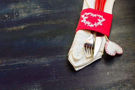 Festive table setting with red rose and heart on rustic wooden table with copyspace