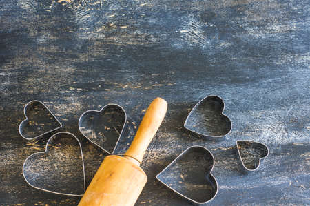 Baking concept for St. Valentines Day with heartshaped cutters and eggs on dark wooden table with copyspaceの写真素材