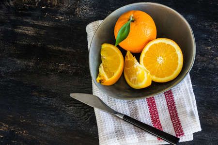 Orange fruits with clises on bright color ceramic plates on dark rustic wooden tableの写真素材