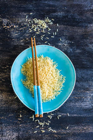 Porcelain plate and rice on dark wooden table with copyspaceの写真素材