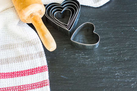 Baking concept for St. Valentines Day with heartshaped cutters and eggs on dark wooden table with...