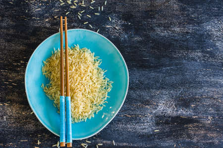 Porcelain plate and rice on dark wooden table with copyspaceの写真素材