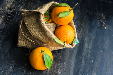 Ripe organic oranges in bag on dark rustic wooden tableの写真素材