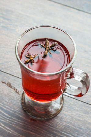 Glass of mulled wine with spices like an anise star and cinnamon sticks on dark wooden backgroundの写真素材